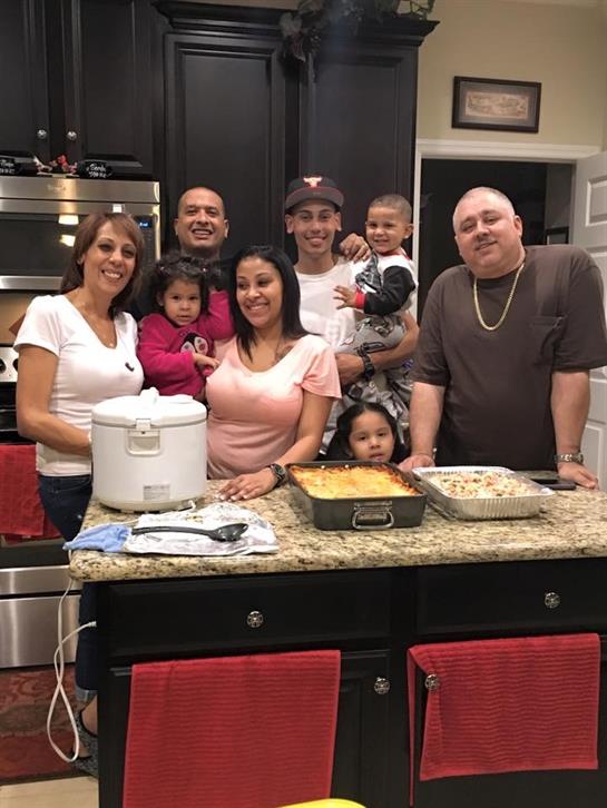 A group of family members poses together in a warm kitchen filled with tasty dishes.