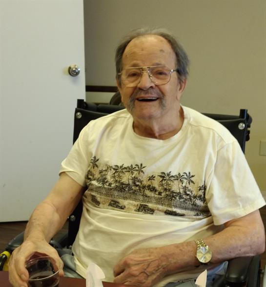 Elderly man seated in wheelchair shares a joyful moment in a community center environment.