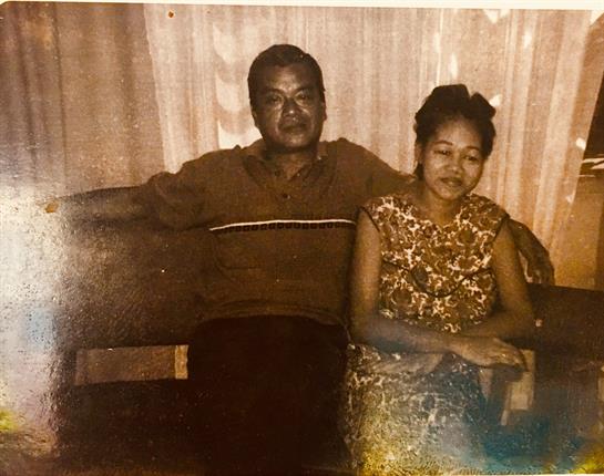 A couple shares a quiet moment, sitting closely together on a couch in a warm living room.