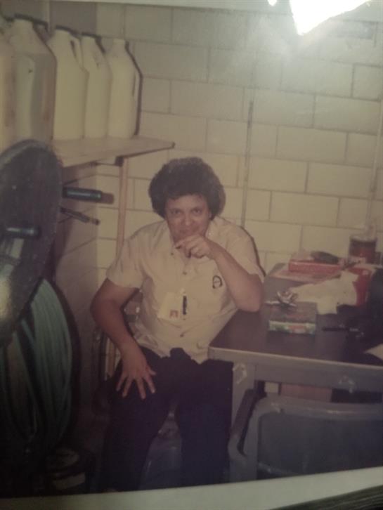 Man reflects while seated in a workshop filled with various tools and equipment.