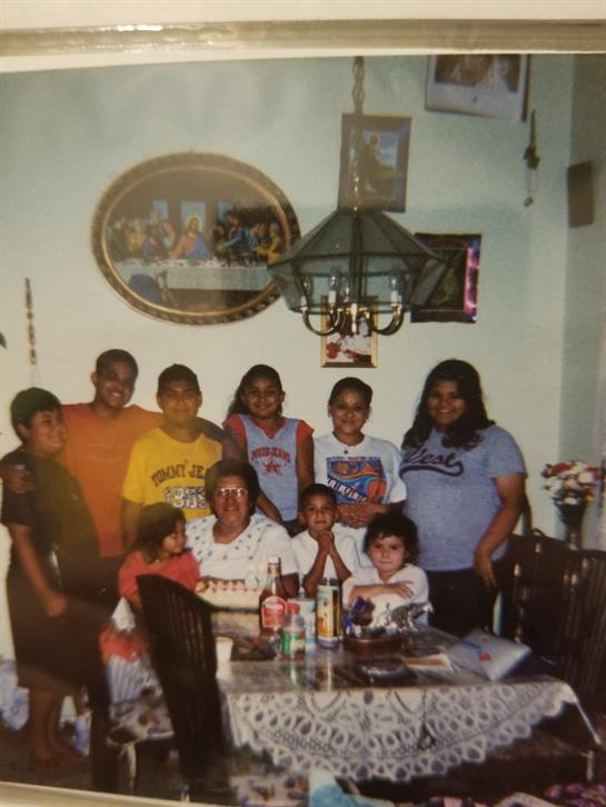 A large family enjoys time together at home around a table filled with food and drinks.