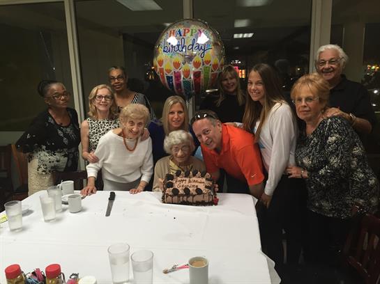 Friends and family happily celebrate a birthday with cake, smiles, and balloons.