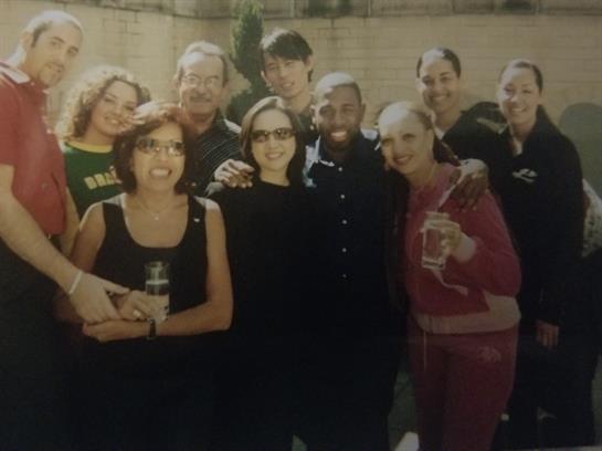 Friends gather outdoors, smiling and enjoying drinks on a warm day in a lively atmosphere.