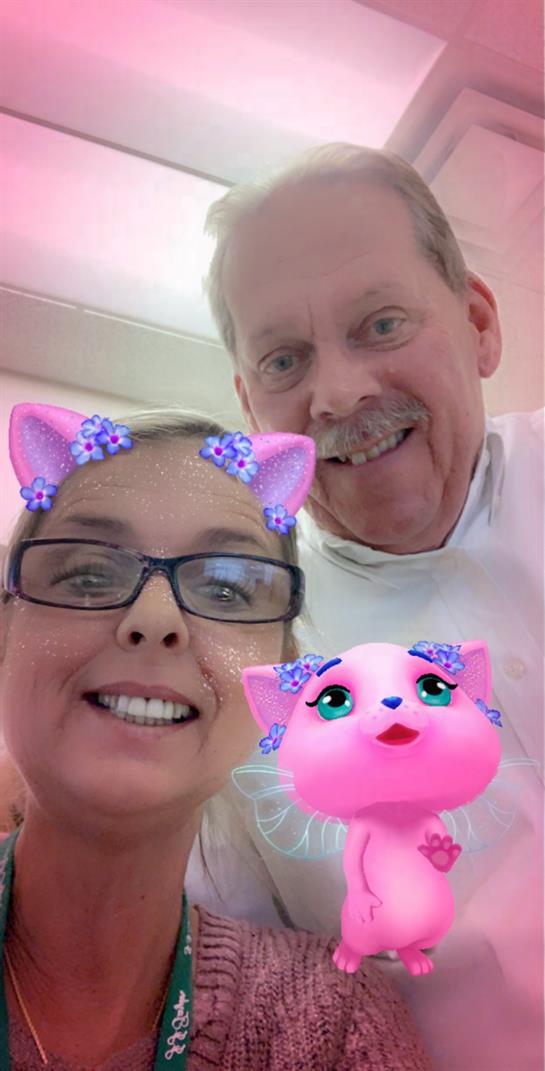 Couple enjoys a lighthearted selfie using playful filters in a relaxed environment.