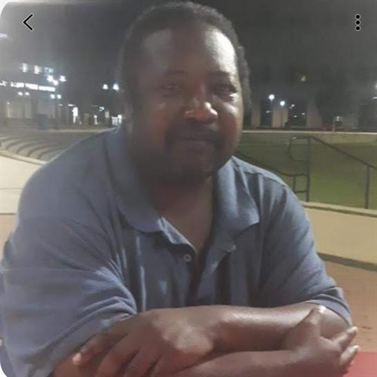 A man relaxes on a bench in the park, enjoying a peaceful evening with lights.