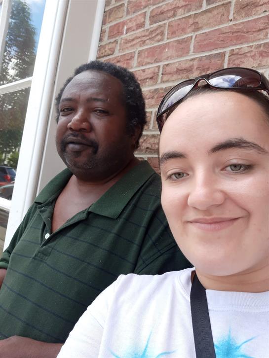 Friends enjoying a sunny afternoon together outside a brick building, smiling for a selfie.