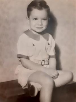 A young child sits cross-legged on the floor in stylish 1960s vintage clothing.