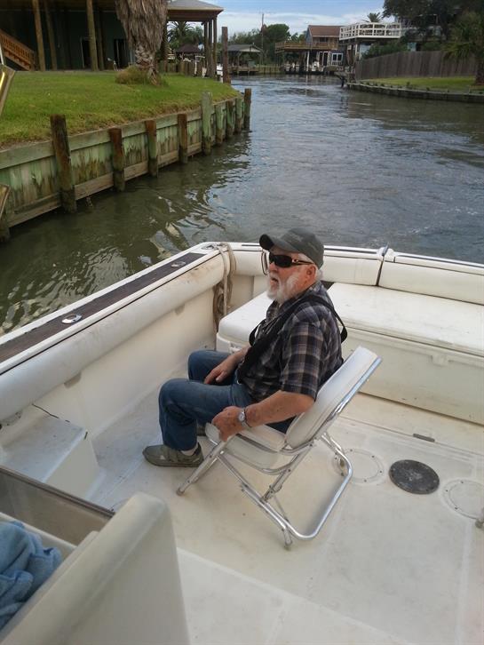 Man in a folding chair on a boat, savoring a peaceful moment by greenery.