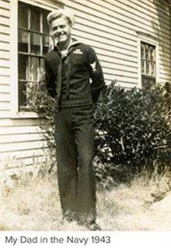 A young sailor poses confidently outside a modest home on a sunny day in rural America.
