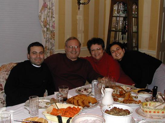Four family members share a joyful meal at a beautifully set table with diverse dishes.