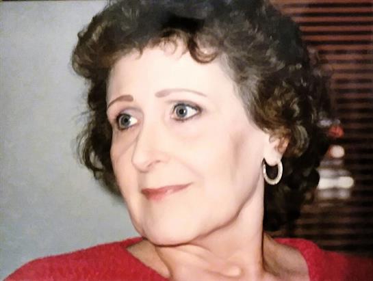 A woman with curly hair and expressive eyes appears to be enjoying a moment indoors at daytime.