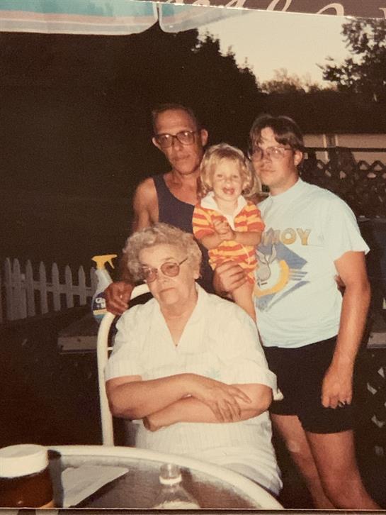 Group of four people enjoying a backyard gathering at dusk, sharing joy and laughter.