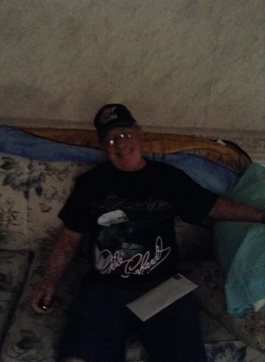 Person sits on a couch, casually dressed, enjoying time indoors with a relaxed demeanor.