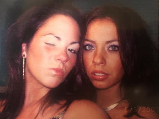 Two women showcase playful and serious expressions while posing together indoors.