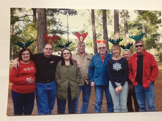 Friends gather outside wearing reindeer antlers, celebrating the holiday season in nature.