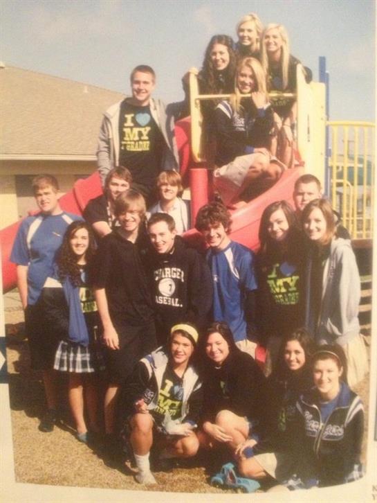 Students gather on a playground, smiling and posing together after an event, enjoying the day.