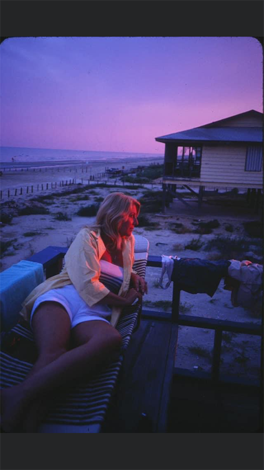 A person sits on a deck, lost in thought as twilight brings a peaceful beach vibe.