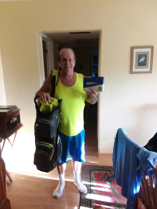 An elderly man in a bright outfit stands at the doorway, ready for a tennis match.