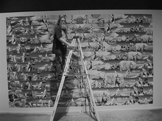 An artist climbs a ladder to add finishing touches to an expansive mural in a gallery.