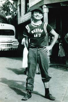 A young man confidently models a vintage sports uniform on a lively street.