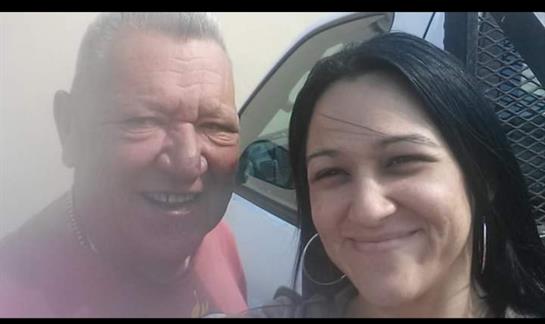 Two friends share a joyful moment with smiles outside a vehicle on a bright day.