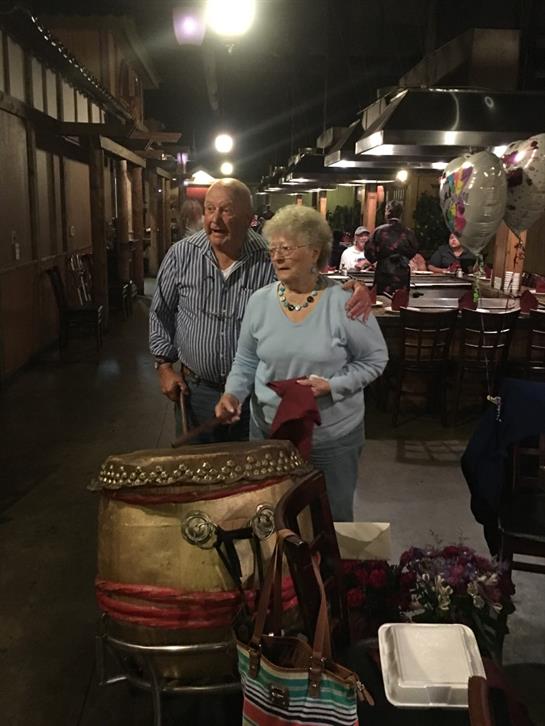 Elderly couple shares a lighthearted moment while dining at a lively restaurant at night.