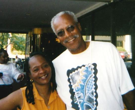Two friends stand together happily in a lively outdoor environment, enjoying their time.