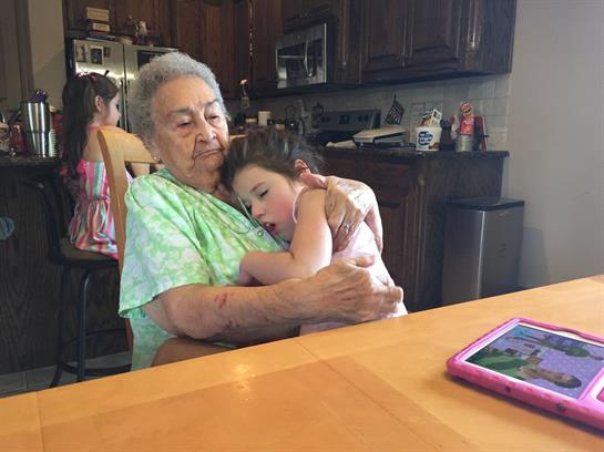 A loving grandmother holds her tired granddaughter in a inviting kitchen atmosphere.