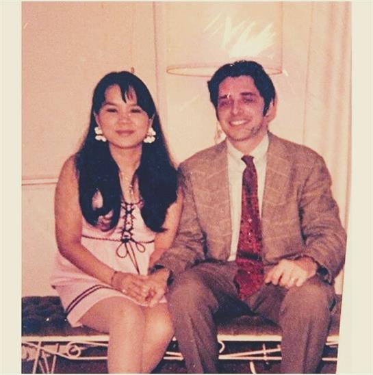 A man and woman pose happily together in elegant vintage clothing, showcasing their styles.