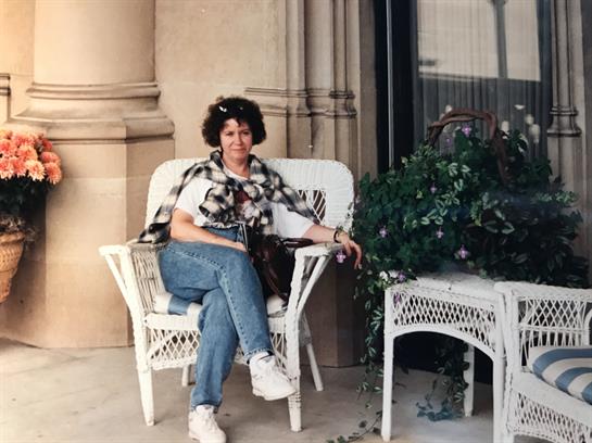 A woman sits comfortably on wicker furniture, enjoying a moment of relaxation in an outdoor setting.