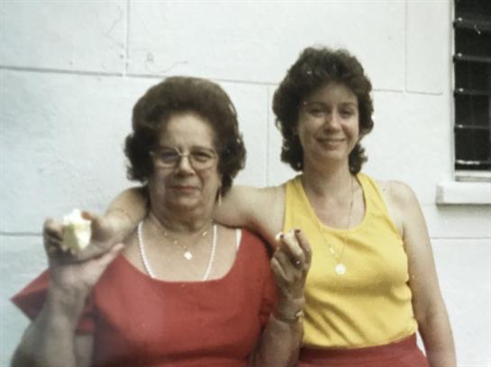 Two women stand next to each other, smiling and holding ice cream cones, enjoying their time.