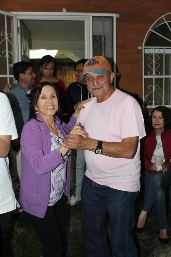 A couple dances together while friends enjoy the lively atmosphere during a backyard gathering.