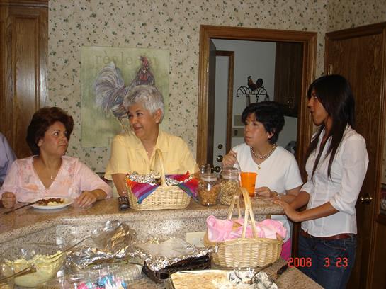 Four family members share stories and laughter around a kitchen counter filled with food.