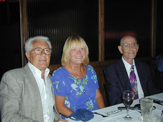 Three friends share smiles and conversation during a festive dinner gathering at a restaurant.