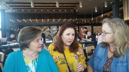 Three friends engage in an animated discussion while enjoying drinks at a vibrant restaurant.