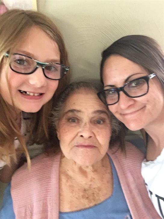Three women from different generations are smiling warmly together, celebrating family bonds.