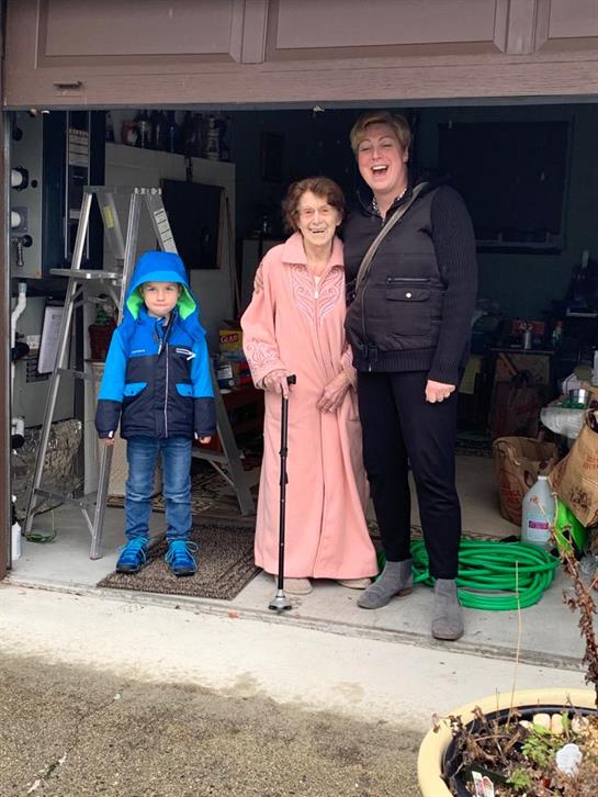 Three people smile together in a garage, showcasing a moment of joy on a rainy day.