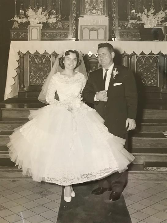 Newlyweds joyfully pose together at the altar, showcasing their elegant wedding attire.