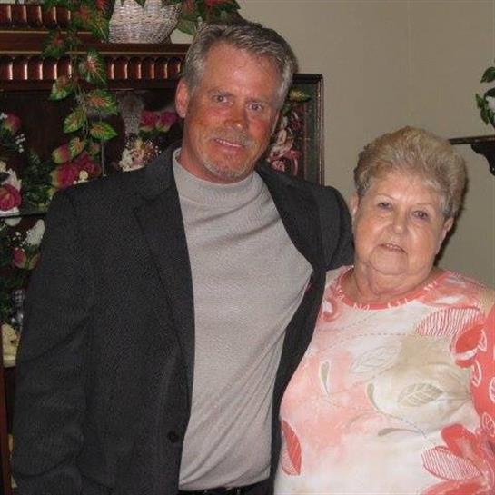 A man and woman pose in a cozy, decorated living room, highlighting their family bond.