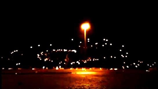 Festive event illuminates the dark sky with sparkling lights and bonfires, attracting joyful crowds.