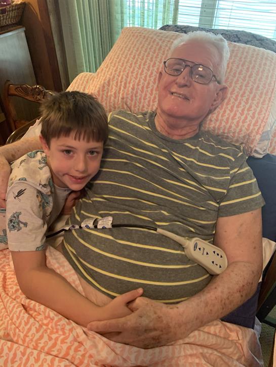 A young boy is embracing his grandfather, sharing a tender moment on a bed in the afternoon.