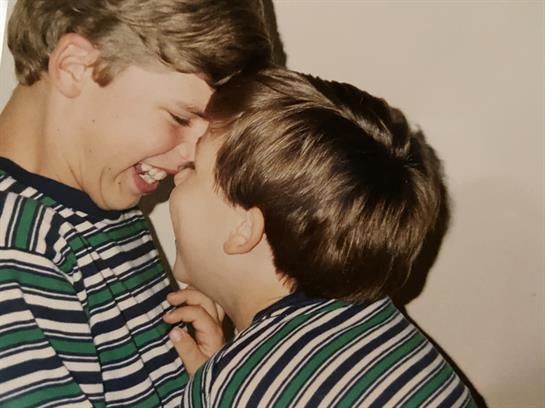 Two young boys are playfully laughing and interacting closely in a cheerful atmosphere.