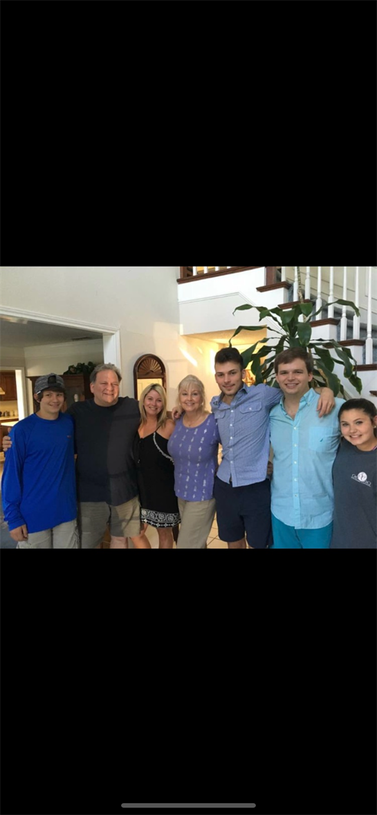 Family members gather in a well-lit living room, enjoying each other's company and smiling broadly.