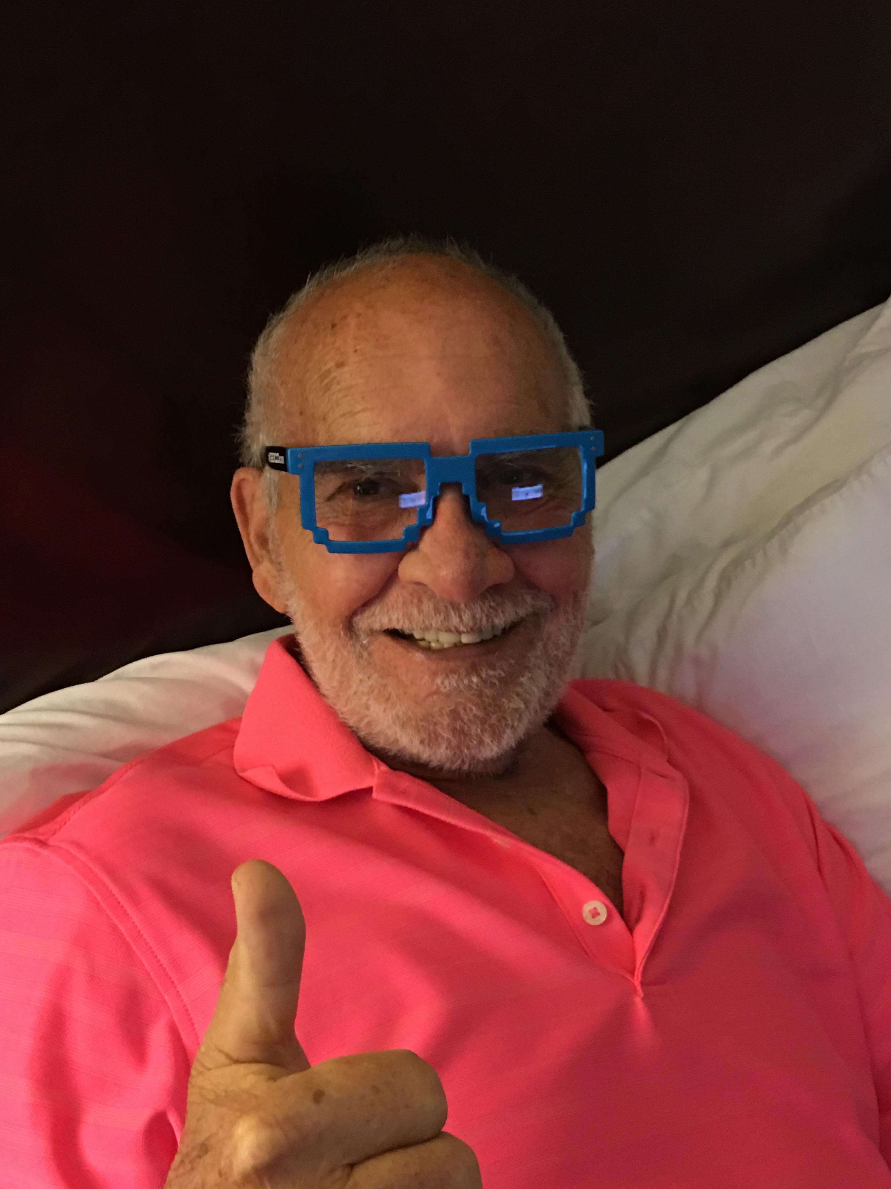 A man wearing blue glasses and a pink shirt