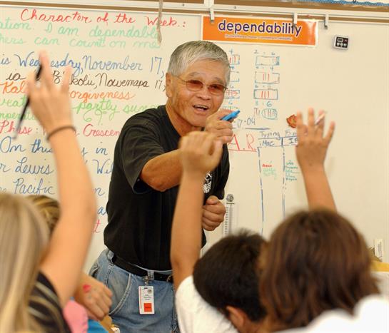 Educator guides an engaging lesson, fostering student interaction in a lively classroom.