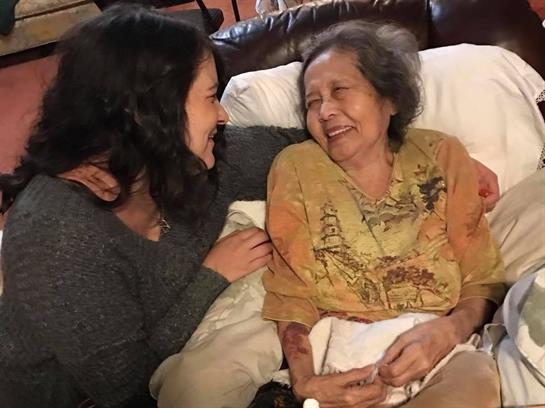 Two women enjoy a joyful conversation together on a couch, showcasing a heartfelt connection.