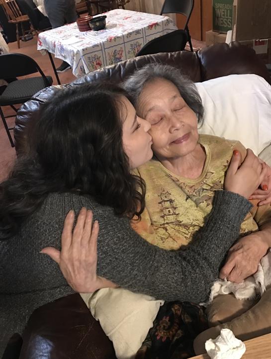 A granddaughter kisses her grandmother on the cheek, sharing a tender moment of love and connection.