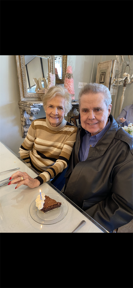 A couple shares a joyful moment celebrating a birthday with cake at a well-decorated table.