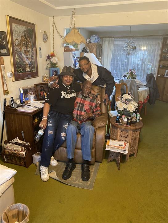 Three family members share joyful moments in a warm living room, highlighting love and connection.