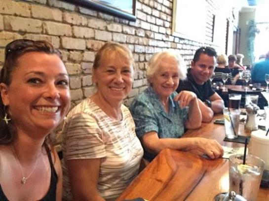 Four people gather at a wooden table in a restaurant, smiling and enjoying their time together.